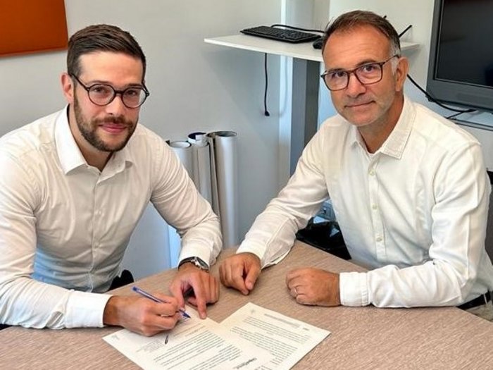 Zusammenarbeit zwischen Potenza Versicherung und KSM Zwei Männer unterschreiben Dokumente an einem Tisch in einem Büro