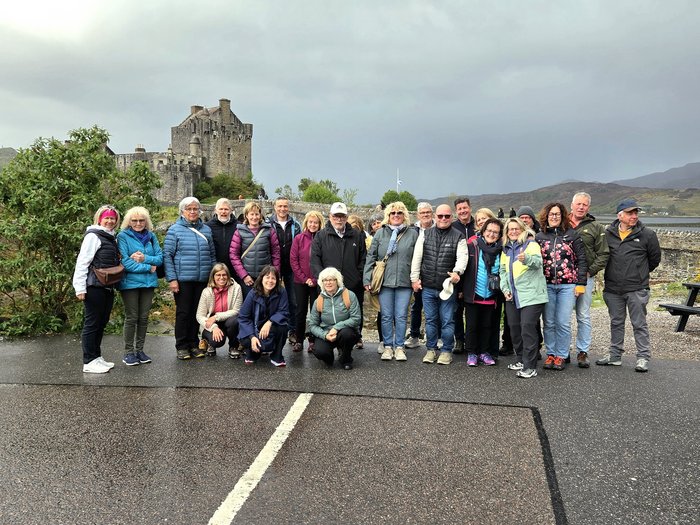 Zwischen Whisky, Highlands und königlichem Flair Gruppenfoto von 25 Personen vor einer alten Burg in einer bergigen Landschaft