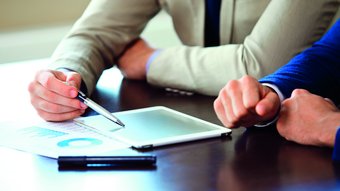 Home Due professionisti discutono dati su tablet e documenti cartacei