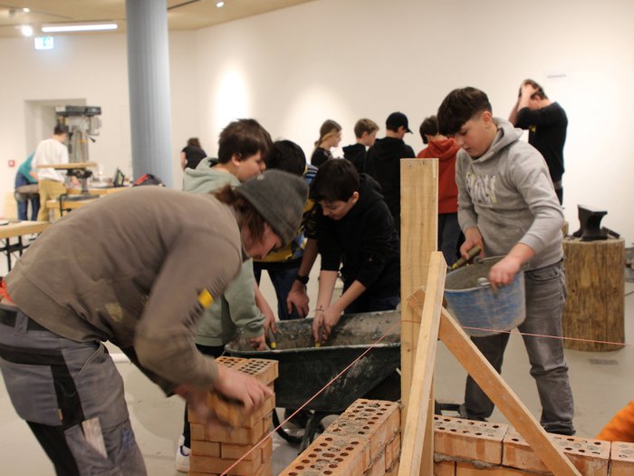 Una settimana intorno all‘artigianato Bambini partecipano a un laboratorio di muratura con mattoni e malta