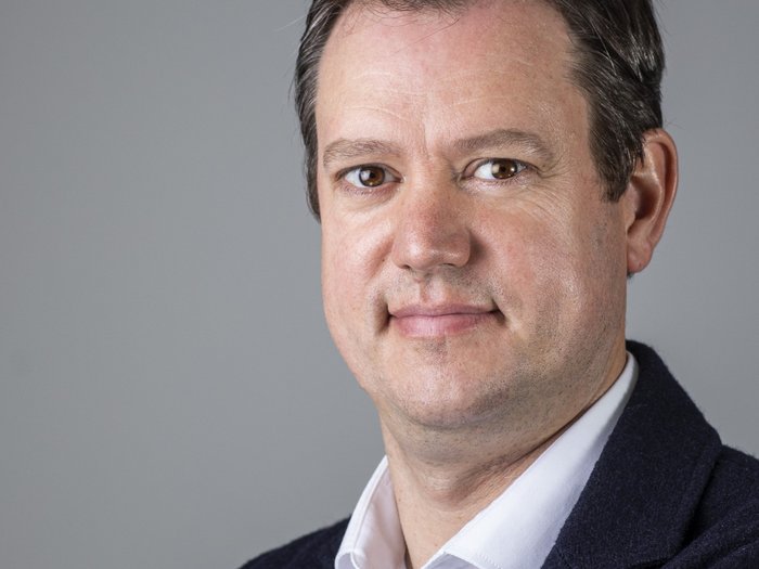 “Burocrazia: niente eccessi!” Ritratto di un uomo sorridente su sfondo grigio