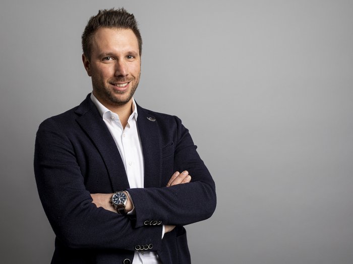 Firmato il nuovo contratto collettivo Edilizia Artigianato Ritratto di uomo sorridente con le braccia incrociate su sfondo grigio