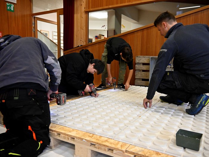 Giornata dell’artigianato a San Genesio Quattro uomini lavorano insieme su una grande lastra bianca con utensili elettrici