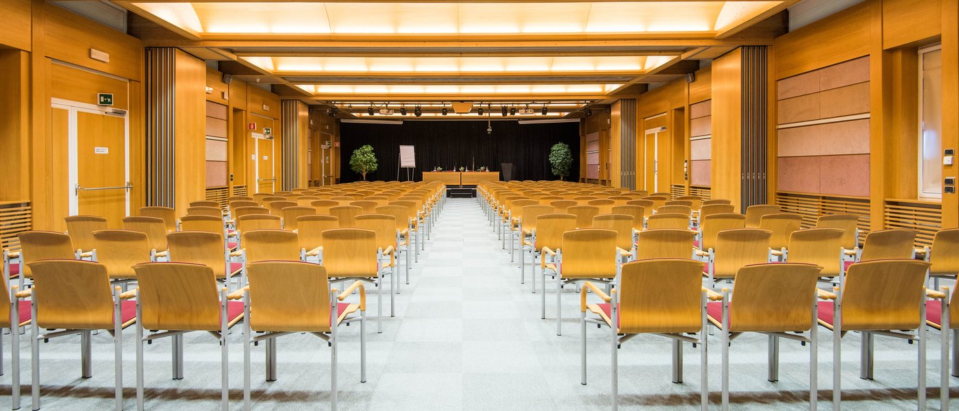 Affitto aule seminari Sala conferenze vuota con sedie in legno e palco sul fondo