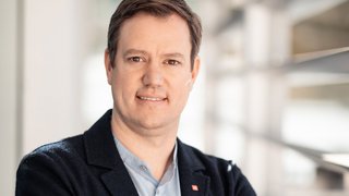 News Porträt eines lächelnden Mannes vor einem hellen Hintergrund