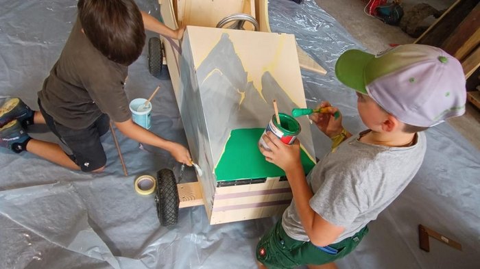 Seifenkistenrennen in St. Felix: Handwerk im Rausch der Geschwindigkeit Kinder bemalen ein hölzernes Seifenkistenauto in einer Werkstatt