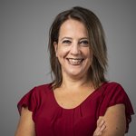 Das lvh-Team Porträt einer lächelnden Frau in rotem Kleid vor grauem Hintergrund