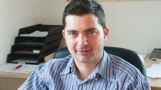 News Mann sitzt im Büro vor Schreibtisch mit Akten und Kalender an der Wand