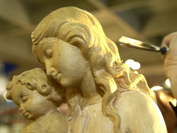 Holzschnitzer Hand schnitzt detaillierte Holzfigur von Mutter mit Kind