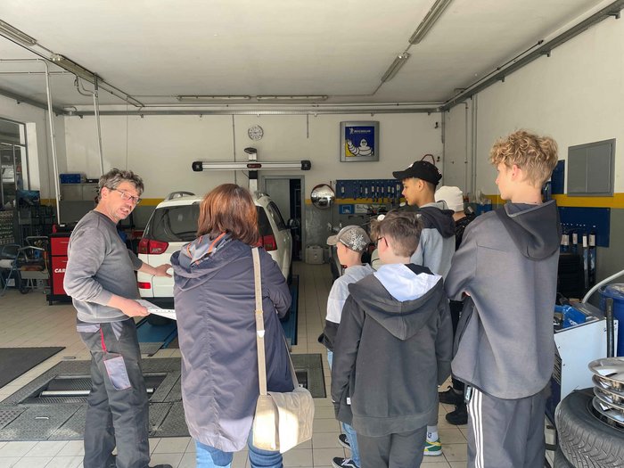 Die Jugendlichen der Mittelschule Latsch über die praktischen Berufe im Hotel- und Gastgewerbe zu informieren: das war das Ziel der Berufsinformationsveranstaltung der Junghandwerkerinnen und Junghandwerker im Wirtschaftsverband für Handwerk und Dienstlei Mechaniker erklärt einer Gruppe Jugendlicher ein Auto in der Werkstatt