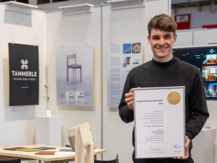 Südtiroler Tischler Emil Tammerle gewinnt Bundespreis auf der IHM 2025 Mann hält Bundesinnovationspreis 2023 auf Möbelausstellung