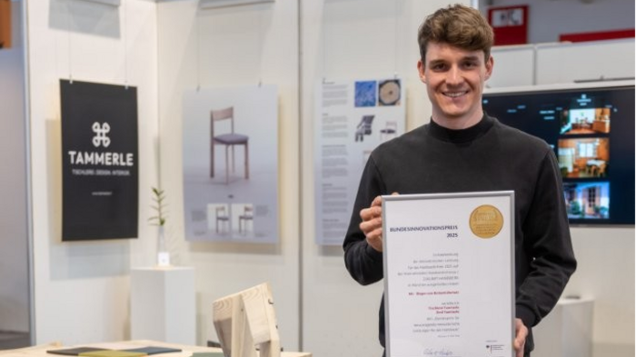 Südtiroler Tischler Emil Tammerle gewinnt Bundespreis auf der IHM 2025 Mann hält Bundesinnovationspreis 2023 auf Möbelausstellung