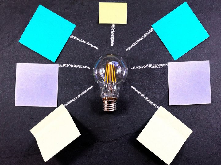 Workshops Glühbirne mit verbundenen Haftnotizen auf Tafel für Ideensammlung