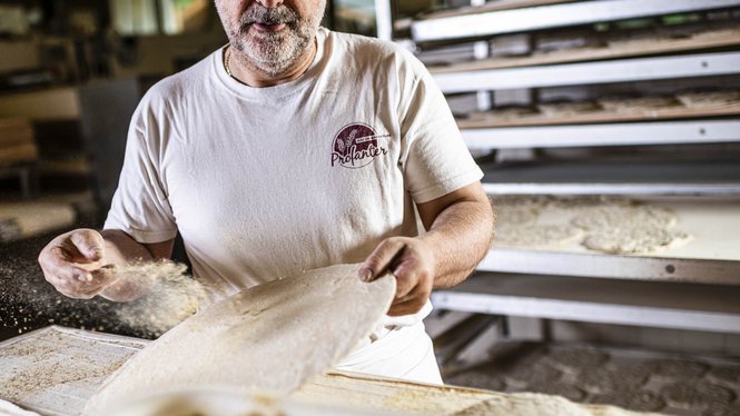 fornaio spolvera la pasta con farina in una panetteria