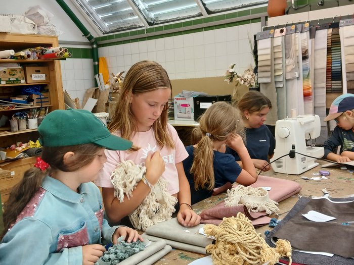 Mit Faden, Fantasie und Fingerfertigkeit – Die KidsAcademy in Brixen macht Handwerk erlebbar Kinder basteln und nähen gemeinsam an einem Tisch in einem Atelier