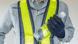 © aomas/ Shutterstock.com Arbeiter in Schutzkleidung hält eine Wasserflasche