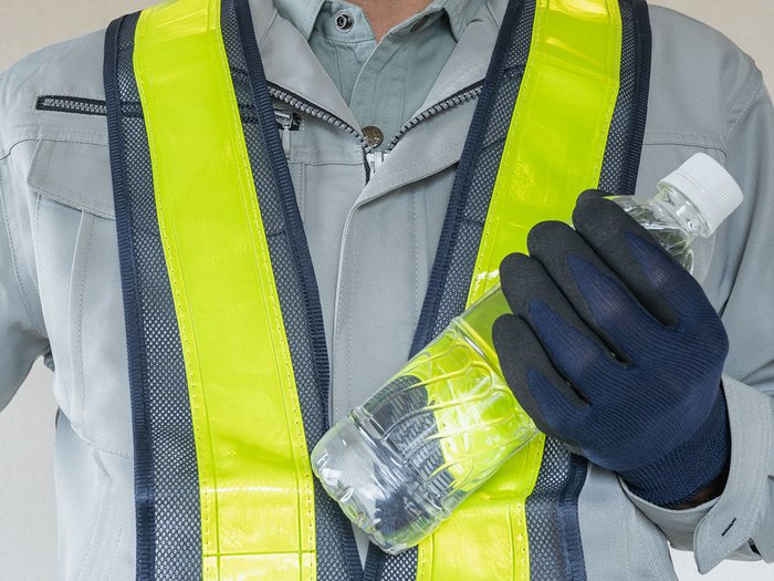 © aomas/ Shutterstock.com Arbeiter in Schutzkleidung hält eine Wasserflasche