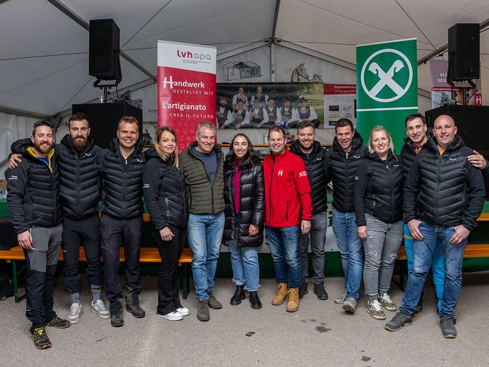 Wo Handwerk auf Pistengaudi trifft: lvh-Wintersportfest begeistert Gruppenfoto von 13 Personen in Winterjacken vor Werbebannern im Zelt