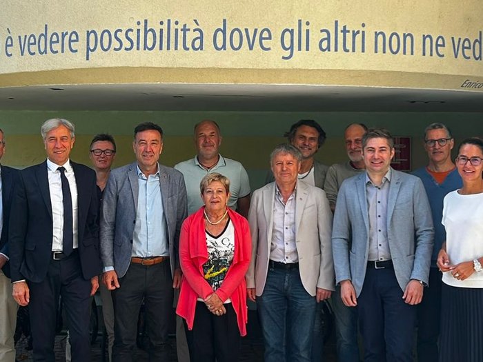 “Incontriamoci a scuola”: insieme per formare i professionisti di domani Foto di gruppo davanti a una parete con la citazione di Enrico Mattei