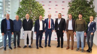 News Zehn Personen stehen vor einer Wand mit LVH-Logos und Pflanzen in einem Büro.