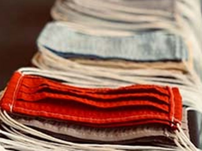 Mundschutz in Handarbeit Mehrere gefaltete Masken in verschiedenen Farben in einer Reihe auf einem Tisch