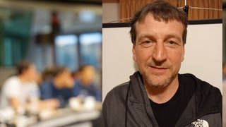 News Mann in schwarzer The North Face Jacke lächelt vor unscharfem Hintergrund