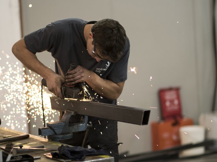 Ja zu Dienstwohnungen und Mitarbeiterunterkünften Mann schleift Metallrohr mit Winkelschleifer, Funken fliegen