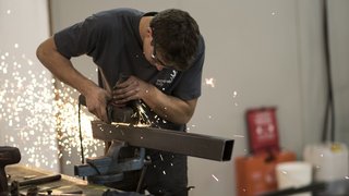 News Mann schleift Metallrohr mit Winkelschleifer, Funken fliegen