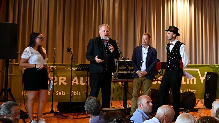 Althandwerker/innen treffen sich in Seis am Schlern Vier Personen sprechen auf Bühne während Publikum zuschaut bei Veranstaltung