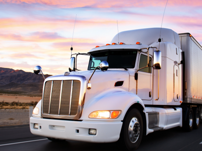 "Unsere Lkw-Fahrer sind die wahren Helden dieser Stunden!" Lastwagen auf Autobahn bei Sonnenuntergang mit Text Cowboys der Autobahn