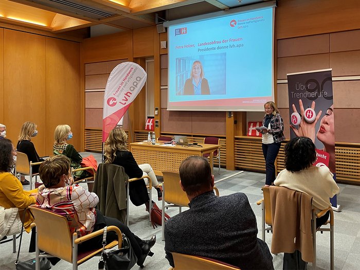 Eine geballte Ladung Frauenpower Frau hält Vortrag vor sitzendem Publikum in einem Konferenzraum