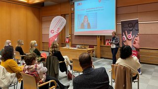 News Frau hält Vortrag vor sitzendem Publikum in einem Konferenzraum