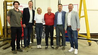 News Sechs Personen stehen in einer Halle vor technischen Geräten und Bannern.