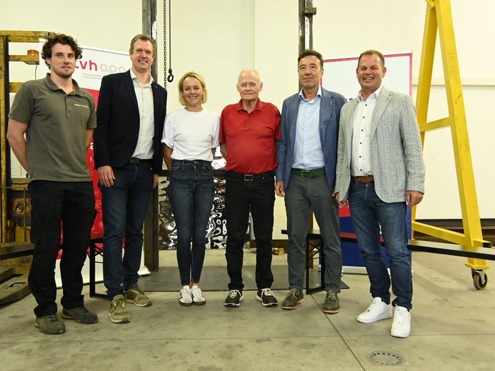 “Dialogo in officina” lvh.apa 2025: L’artigianato tra sfide e opportunità Sei persone in piedi in un capannone davanti a macchinari e striscioni.