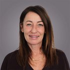 Alessandra Vegro Primo piano di donna sorridente con capelli castani su sfondo grigio