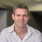 Bodenleger Porträt eines lächelnden Mannes in weißem Hemd vor unscharfem Hintergrund