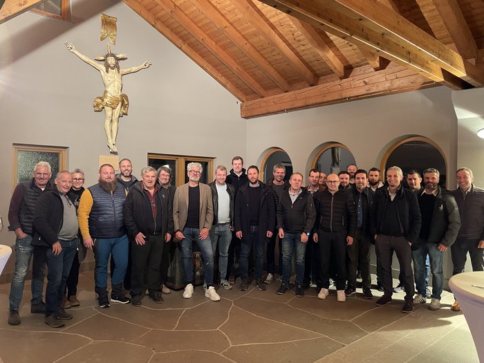 Fritz Ploner nuovo presidente del gruppo edilizia di lvh.apa Foto di gruppo di uomini in una stanza con travi in legno e crocifisso al muro