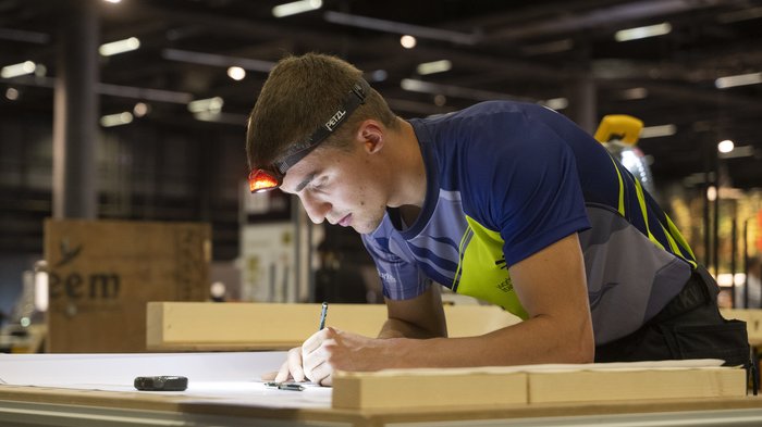 WorldSkills 2022: iniziate le prime competizioni Uomo con lampada frontale disegna progetti su un tavolo in officina