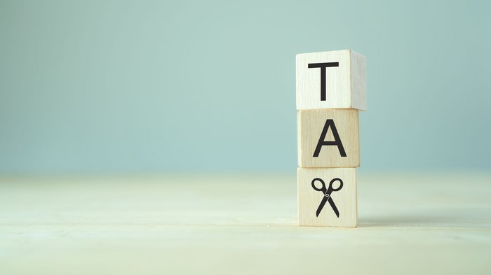 Ein gerechteres Steuersystem Holzwürfel mit Buchstaben T, A und einer Schere auf hellem Hintergrund