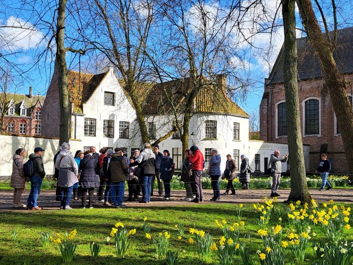 Althandwerker/innen im Herzen der Europäischen Union Gruppe von Menschen in einem Park mit gelben Blumen und historischen Gebäuden im Hintergrund