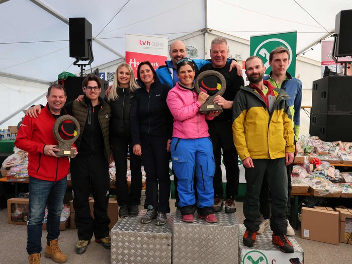 Wo Handwerk auf Pistengaudi trifft: lvh-Wintersportfest begeistert Gruppe von neun Menschen auf Siegertreppchen mit zwei Trophäen in einem Zelt
