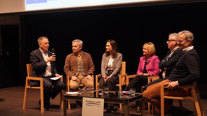 Nachfrage nach Coworking und Betreuung wächst Podiumsdiskussion mit sechs Personen bei einer Veranstaltung, Tisch mit Gläsern im Vordergrund