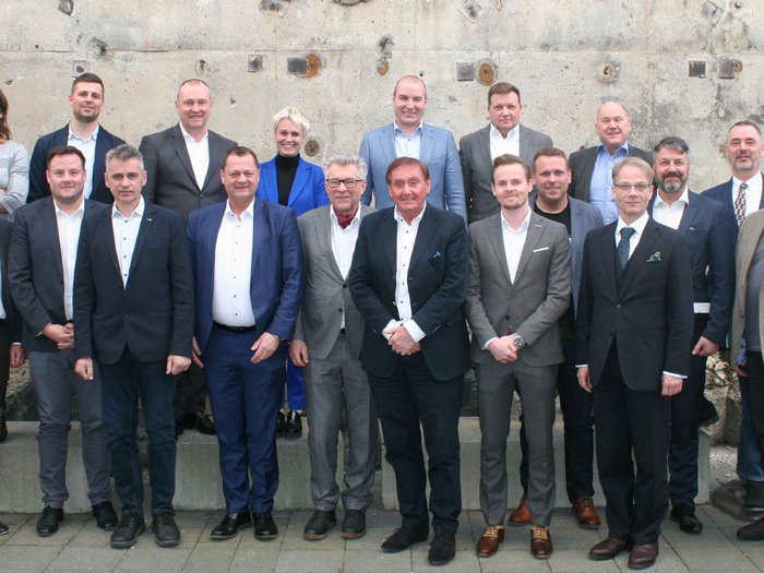 Südtirolerin im Vorstand des Weltverbandes der Karosseriebauer Gruppenfoto von 19 Personen vor einer Betonwand im Freien