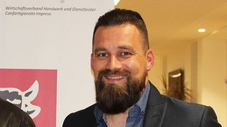 News Porträt eines lächelnden Mannes mit Bart in Anzugjacke