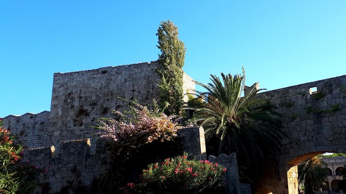 Althandwerker Rhodos 2022 © lvh.apa Historische Steinmauer mit Arkaden und Palmen unter klarem blauem Himmel