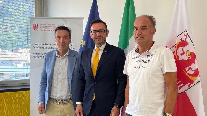 Werbesteuer in Südtirol: Staat ermöglicht höheres Inkasso – aber wo bleibt der Bürokratieabbau? Drei Männer stehen vor EU-, italienischen und Südtiroler Flaggen