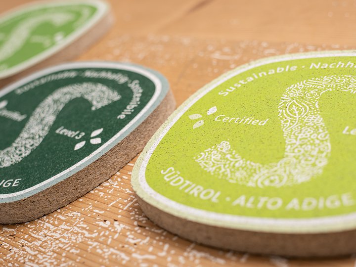Artigianato sostenibile Etichette di sostenibilità del Sudtirolo in verde e scuro su superficie in legno