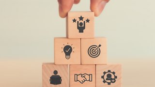 Webinare Hand stapelt Holzklötze mit Symbolen für Teamwork, Idee, Ziel und Erfolg