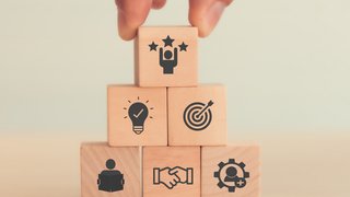 Webinare Hand stapelt Holzklötze mit Symbolen für Teamwork, Idee, Ziel und Erfolg