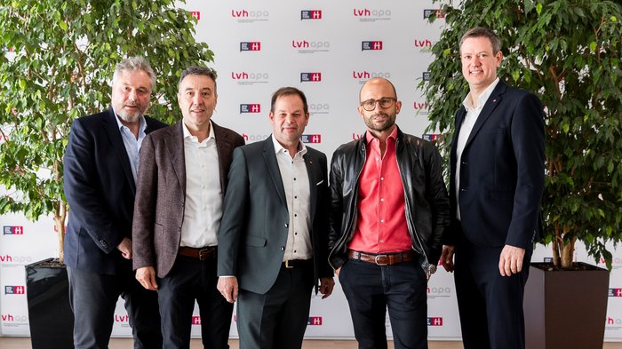 “Fieri di fare artigianato”: l'Assemblea provinciale dell'artigianato altoatesino celebra successi, persone e visioni Cinque uomini in abbigliamento formale davanti a striscione aziendale e piante